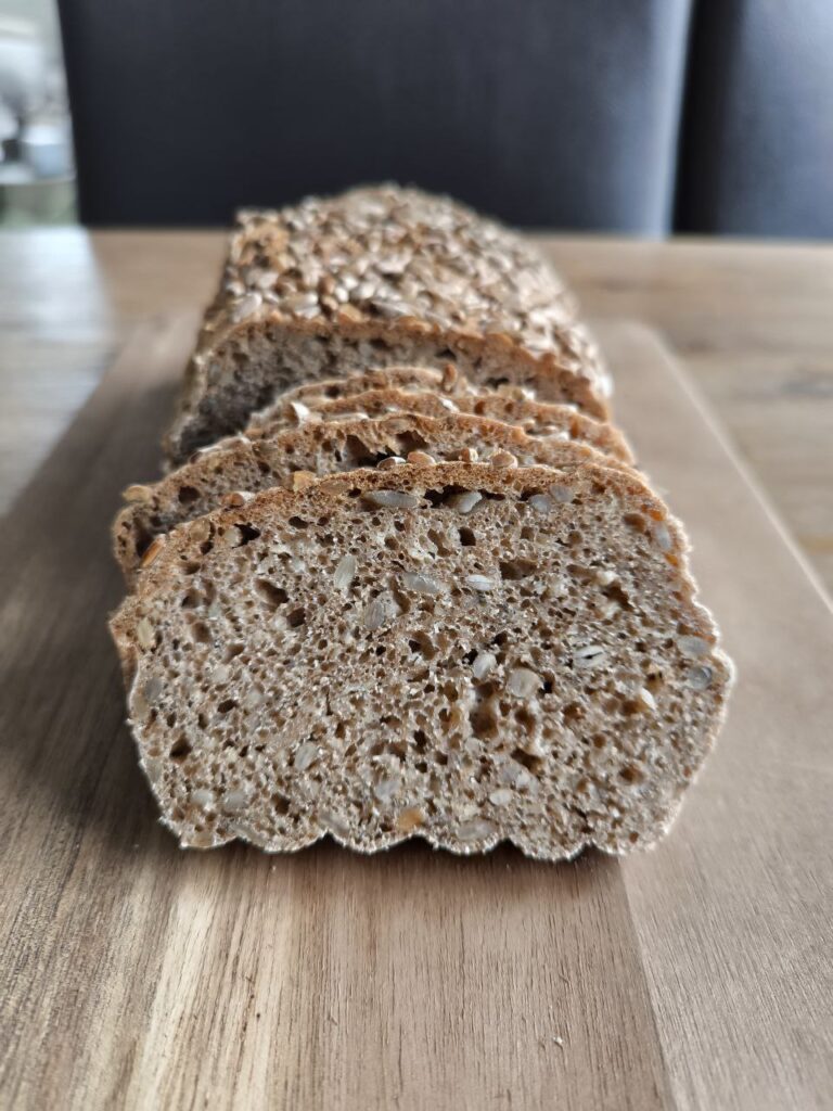 Saftiges Dinkel-Vollkornbrot mit lockerer Krume, aufgeschnitten auf Holzbrett