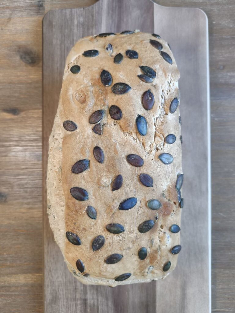 Dinkelbrot mit gerösteten Kürbiskernen frisch gebacken auf einem Holzbrett
